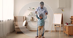 Indian little boy jumping holding father hands having fun indoor