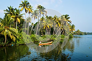 Indian local man in a canoe on river in along the kollam kottapuram waterway in the Kerala backwaters, India