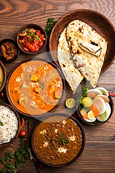 Indian lunch or dinner items like dal, paneer butter masala, roti, rice, salad