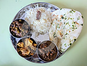 Indian lunch served in a traditional silver plate  with naan rajma paneer mushroom peas curry and zeera rice