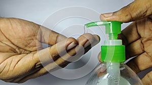 Indian Male hands pushing on Alcohol based Hand Sanitizer dispenser and squeeze out sanitizer gel on palm, closeup shot against