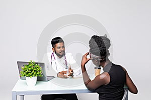 Indian man doctor have a consultation with depressed african female patient in clinic