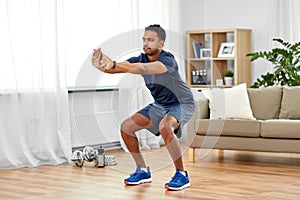 Indian man exercising and doing squats at home