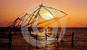 Indian man fishing under the great Chinese nets at Cochin, Kerela, India.