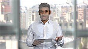 Indian man giving presentation speech in office holding tablet pc.