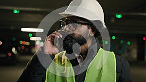 Indian man handyman worker foreman contractor at parking talking phone builder in helmet and glasses industrial