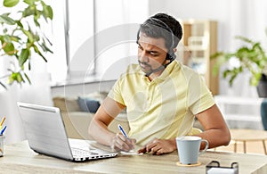 Indian man with headset and laptop working at home