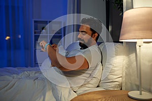 indian man with health tracker in bed at night