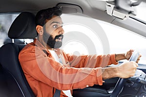 Indian Man holding steering wheel, looking in shock driving automobile
