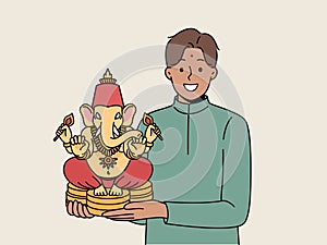 Indian man holds figurine Lord ganesha and smiles demonstrating amulet that brings good luck