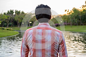 Indian man looking at scenic view of the lake in peaceful green