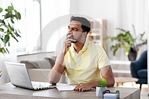 Indian man with notebook and laptop at home office