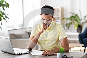 Indian man with notebook and laptop at home office