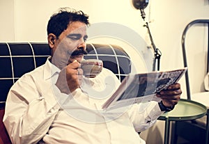 Indian man reading newspaper at home