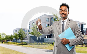 Indian man realtor with key and folder in city