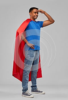 Indian man in red superhero cape looking far away