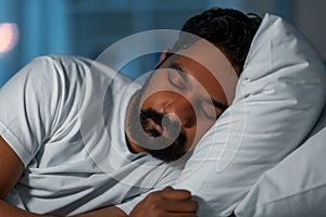 indian man sleeping in bed at home at night