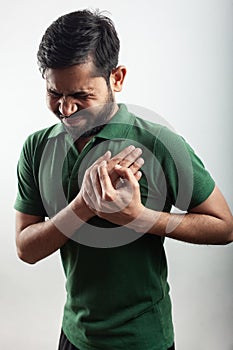 Indian man suffering from heart attack and holding chest with grimace expression