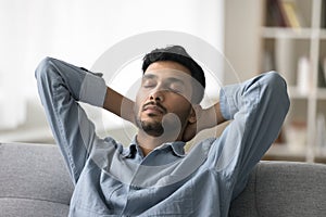 Indian man take break leaned on soft couch