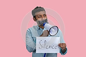 Indian man taped mouth speaks in megaphone.