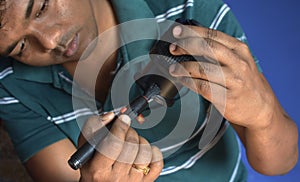 An Indian man technician inspecting and cleaning dslr or mirrorless camera lens