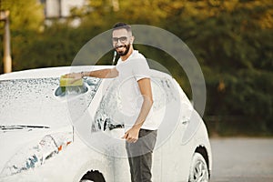 Indian man washing his white transportation on car wash