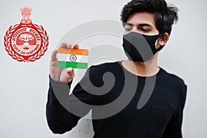 Indian man wear all black and face mask, hold India flag in hand isolated on white background with Haryana state emblem .