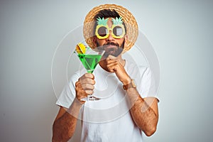 Indian man wearing summer funny look drinking cocktail over isolated white background serious face thinking about question, very