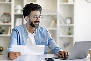 Indian Man Working With Papers And Laptop At Home Office