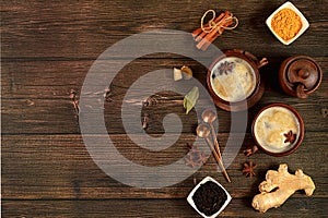 Indian masala chai tea with milk, ginger, anise and cinnamon on an old wooden table. Traditional drink with spices, cafe concept,