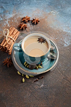 Indian masala chai tea. Spiced tea with milk on dark rusty background.