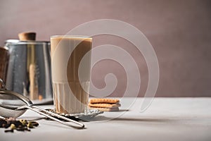 Indian masala chai tea. Traditional glass with strainer and chai spices.