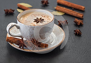 Indian Masala chai tea. Traditional Indian hot drink with milk and spices on dark stone background closeup