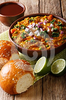 Indian Mumbai food Pav bhaji from vegetables with bread close-up in a bowl. vertical