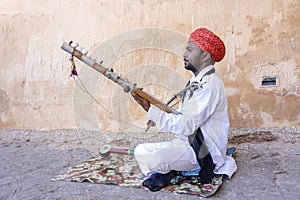 Indian musician play on traditional music instrument for tourists. India