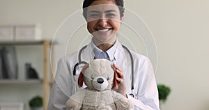 Indian paediatrician holding fluffy toy smile look at camera
