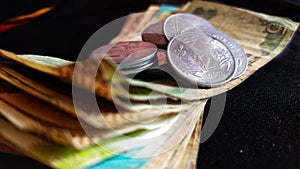 Indian paper currency with coins on isolated black background, concept of savings and investment