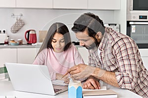 Indian parent dad helping school child teen daughter studying online at home.