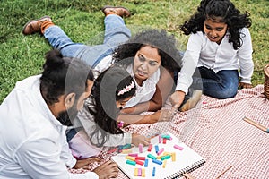 Indian parents having fun at city park playing with wood toys with their daughter and son - Main focus on mother face