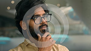 Indian pensive man in eyeglasses thinking. Close up thoughtful male face look distance indoors pondering business idea
