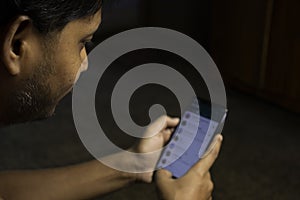 an Indian person is using whatsapp application in smartphone in a dark room with selective focus