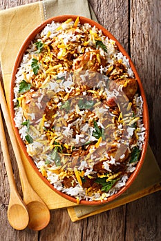 Indian pilaf biryani with chicken, onion, lemon, spices and cilantro close-up. Vertical top view