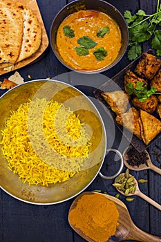 Indian pilau rice in balti dish served with chicken tikka masala curry and side dishes photo