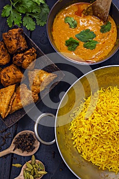 Indian pilau rice in balti dish served with chicken tikka masala curry and side dishes