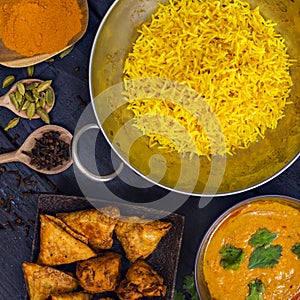 Indian pilau rice in balti dish served with chicken tikka masala curry and side dishes