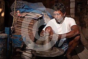 Indian potter making small pot or Diya for Diwali with clay on potters wheel in his small factory.Handwork craft