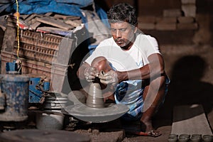 Indian potter making small pot or Diya for Diwali with clay on potters wheel in his small factory.Handwork craft