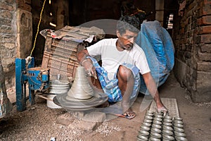 Indian potter making small pot or Diya for Diwali with clay on potters wheel in his small factory. Manufacturing traditional