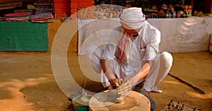 Indian potter throwing the potter's wheel and shaping ceramic vessel and clay ware. Udaipur, Rajasthan, India