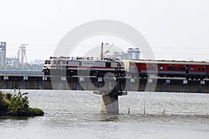 indian railway train moving very quickly on a bridge over the river in kerala